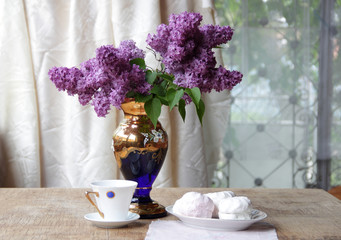 Still-life with a zephyr, a cup of tea and a lilac bouquet