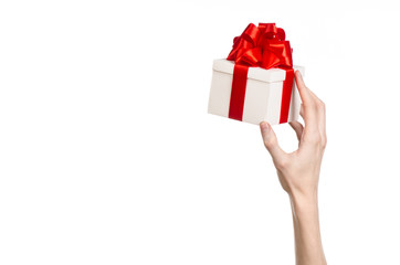 hand holding a gift wrapped in white box with red ribbon and bow