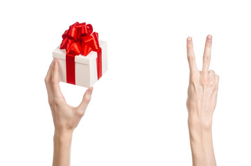 hand holding a gift wrapped in white box with red ribbon and bow