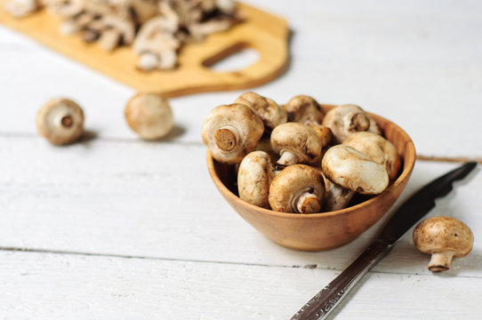 Sliced champignons on board and wooden bowl