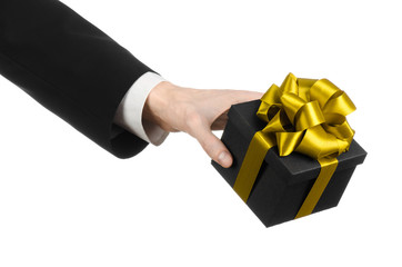man in a black suit holding gift packaged in a black box