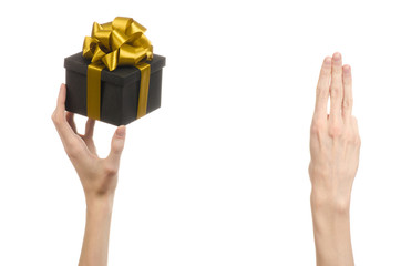 hand holding a gift wrapped in a black box with gold ribbon