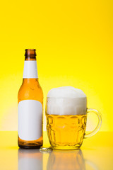 Mug with foamy beer and empty bottle