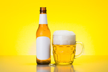 Mug with foamy beer and empty bottle