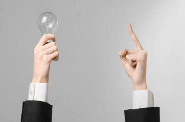 man's hand in a black suit holding a light bulb in studio 