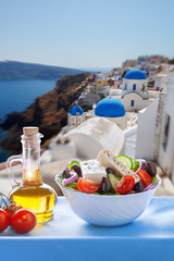 Greek salad against churches in Santorini island, Greece