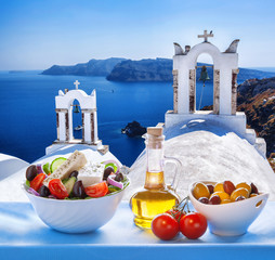 Greek salad against churches in Santorini island, Greece