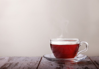 Glass cup with tea and a lemon on a glass saucer  