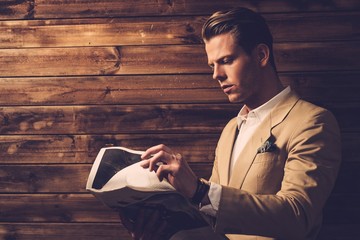 Stylish man with newspaper in rural cottage interior