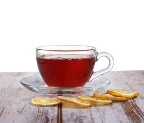 Glass cup with tea and a lemon on a glass saucer isolated