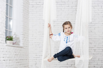 Young girl in embroidery on swing