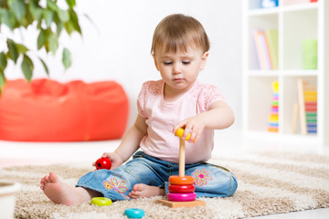 Adorable toddler girl playing in nursery room