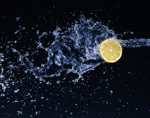 Half a lime falling into the water isolated on a black 