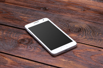 Smart phone with blank screen lying on wooden table - Powered by Adobe