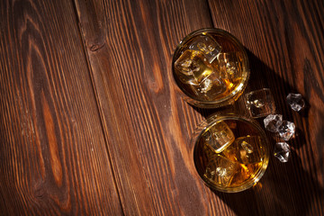 Obraz na płótnie Canvas Glasses of whiskey with ice on wood