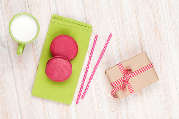 Colorful macarons, cup of milk and gift box