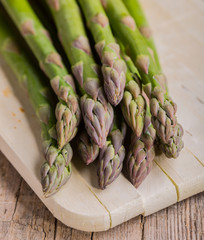 bunch of green asparagus on cutting board