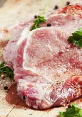 Raw meat steak with spices on a wooden board, selective focus