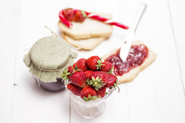 strawberries and jam on bread, white wooden background