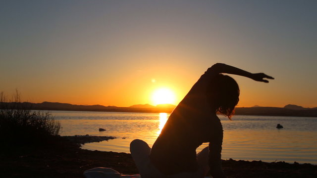 Healthy woman meditating at sunset