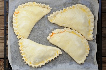 Four raw calzone pizzas on papered frying pan