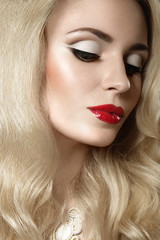 Fototapeta premium Beautiful blonde woman with evening make-up and red lips. Picture taken in the studio on a black background.