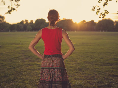 Woman standing in park admiring the sunset