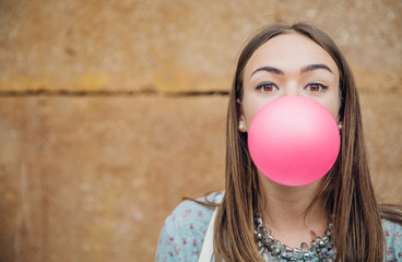 Young teenage girl blowing pink bubble gum - obrazy, fototapety, plakaty