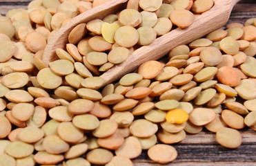 Heap of green lentil with spoon on wooden background
