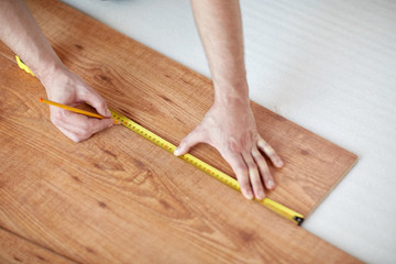 close up of male hands measuring flooring