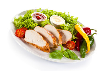 Roast chicken fillet and vegetables on white background