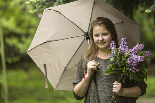 Portrait of teen girl with an umbrella and a bouquet of lilacs.