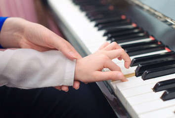 Fototapeta na wymiar Woman teaching little girl to play the piano.