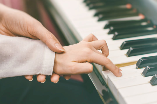 Woman teaching little girl to play the piano.