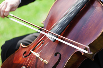 Man's hands playing violoncello outdoors