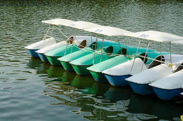 A row of colorful pedal boats on a lake