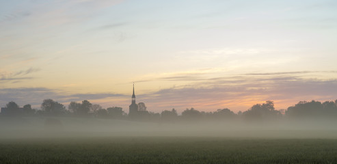 Fototapeta na wymiar beautiful, misty sunrise on a field near the village