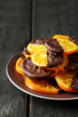 Delicious slices of orange coated chocolate on plate 
