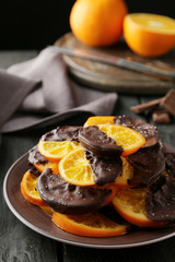 Delicious slices of orange coated chocolate on plate 