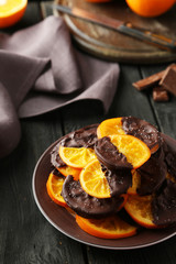 Delicious slices of orange coated chocolate on plate 