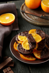 Delicious slices of orange coated chocolate on plate 