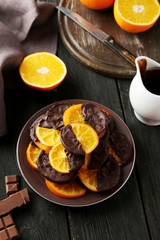 Delicious slices of orange coated chocolate on plate 
