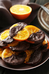 Delicious slices of orange coated chocolate on plate 