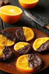 Delicious slices of orange coated chocolate on plate 