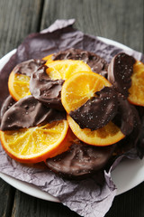 Delicious slices of orange coated chocolate on plate 