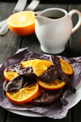 Fototapeta na wymiar Delicious slices of orange coated chocolate on plate 