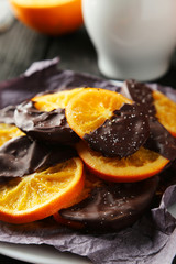 Delicious slices of orange coated chocolate on plate 