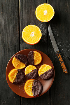 Delicious slices of orange coated chocolate on plate 