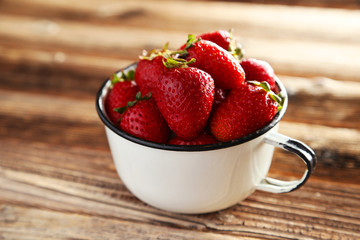Strawberries in cup on brown wooden background