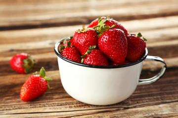 Strawberries in cup on brown wooden background